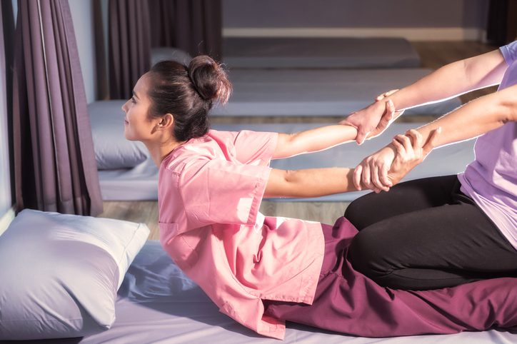 Therapist giving Thai massage to a woman
